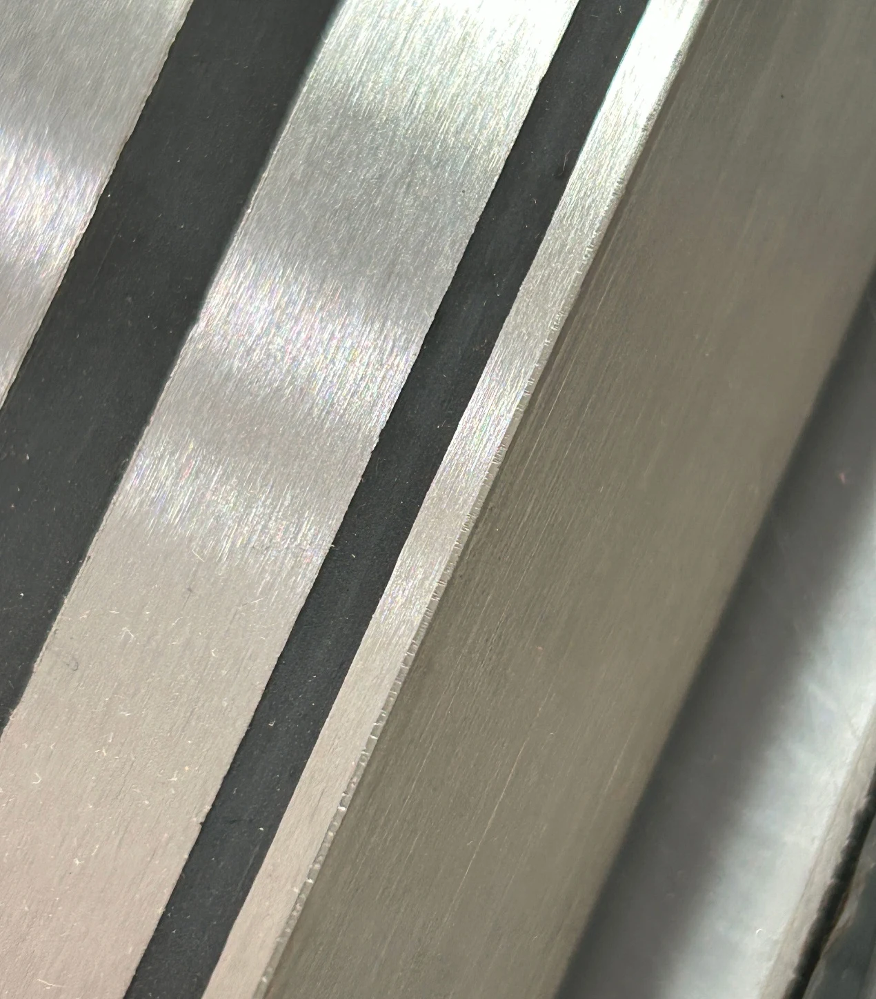Close-up of finished metal working faces separated by dark encapsulation bands